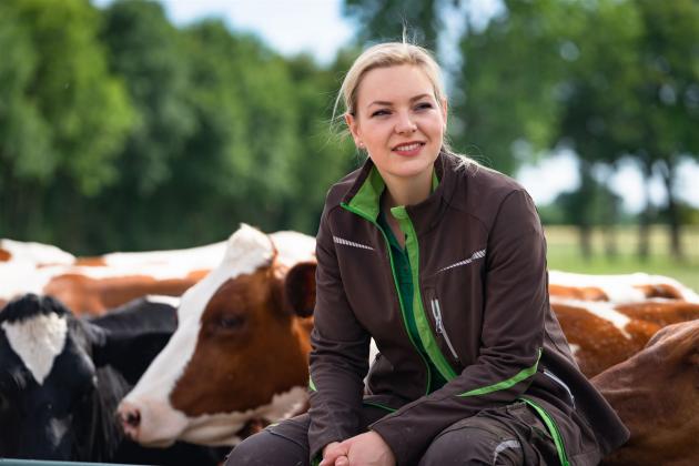 Landwirtin sitz bei Rindern auf Zaun
