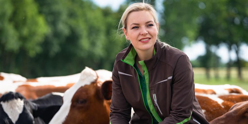 Landwirtin sitz bei Rindern auf Zaun